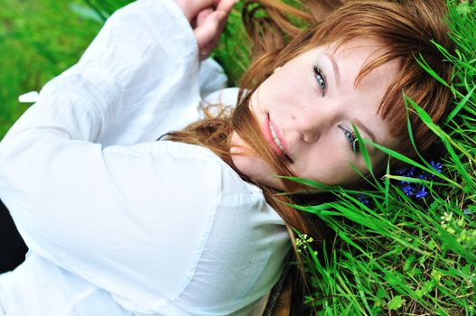 redheaded girl laying on the spring meadow