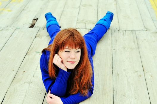 cunning redheaded ten girl laying on the pier