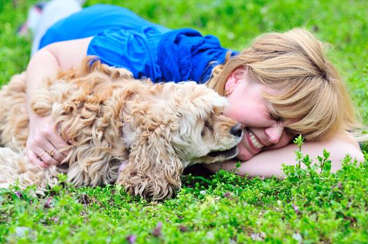 woman and her dog having fun in green grass