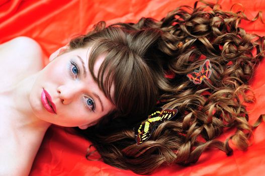 longhaired beautiful girl with buterfly in her hair over the red