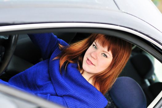 redheaded teen girl drivering a dark car 