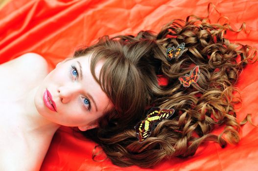 long haired beautiful girl with butterfly in her hair over the red