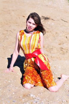 summer girl sitting on the sand in windy day