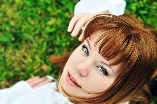 redheaded girl laying on the spring meadow

