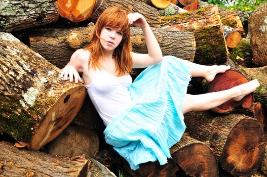 beautiful redheaded girl having sunbath on cord wood
