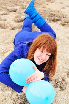 redheaded girl having fun with balloons on the beach