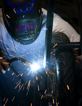 Welder working on the metal fork of a motorcycle