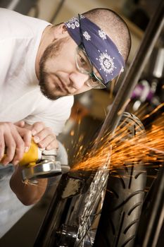 Hispaninc man using grinder tool on the front fork of motorcycle