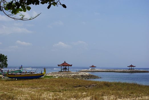 It's some typical little boat from Bali on the beach with three little temple on the Indian ocean in Bali