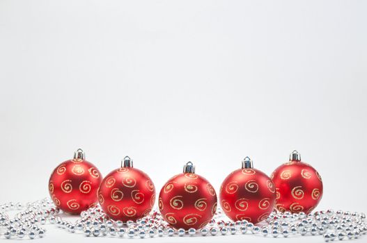 Red Christmas balls decorated in gold clitter on white background with silver beads.