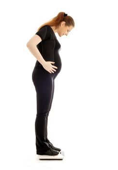 lovely pregnant lady weighing oneself over white background