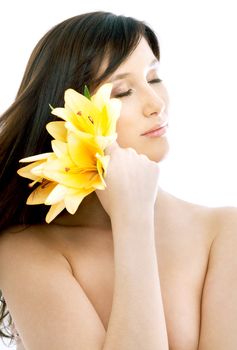 topless brunette with yellow lily flowers in spa