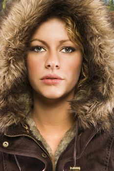 Caucasian young adult woman wearing fur hood looking at viewer.