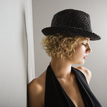 Profile of Caucasian young adult woman wearing fedora hat with eyes closed.