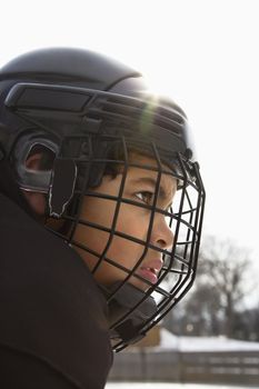 Close up of ice hockey player boy in cage helmet with look of concentration.