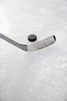 Close up of ice hockey stick on ice rink in position to hit hockey puck.