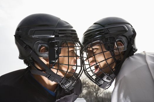 Two ice hockey players in uniform facing off trying to intimidate eachother.