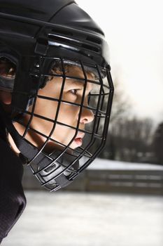 Ice hockey player boy in uniform and cage helmet concentrating.