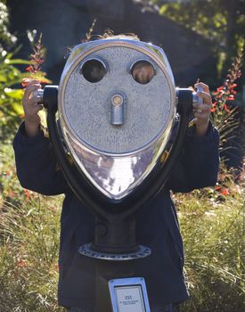 Girl using a telescope looking towards the camera