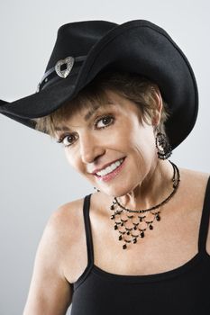 Head and shoulder portrait of pretty Caucasian woman smiling and wearing cowboy hat.