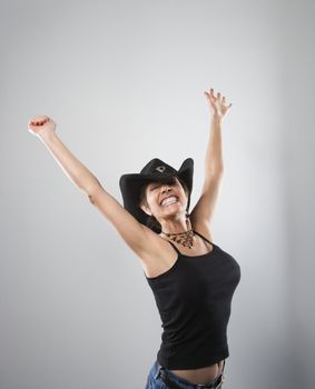 Portrait of woman smiling and holding arms up in air.