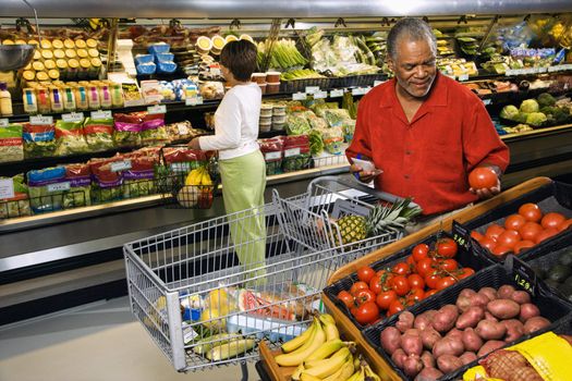 Middle aged African American man and woman in grocery store shopping for produce.