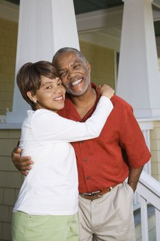 African American middle aged couple hugging and smiling at viewer.