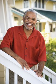 African American middle aged man smiling at viewer and leaning on stairway railing.
