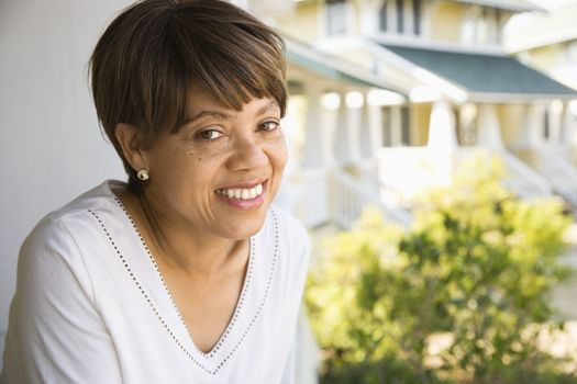African American middle aged woman smiling at viewer outside home.
