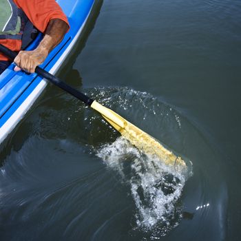 African American male arm paddling kayak.