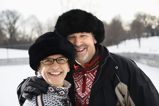 Portrait of Caucasian middle aged man and woman wearing black winter hats smiling at viewer.