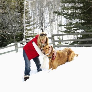 Woman with arms around dog in snow covered Colorado landscape.
