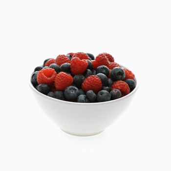 Bowl of mixed blueberries and raspberries on white background.