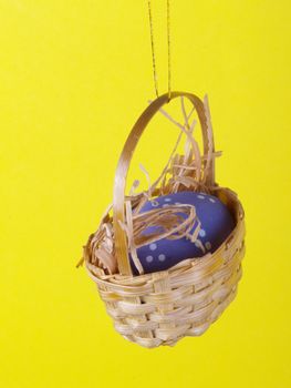 easter decoration miniature basket with egg over yellow