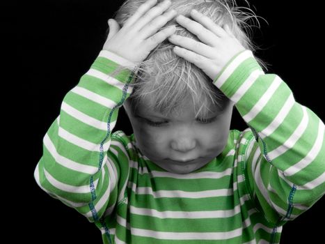 Little boy with hands on his head on black background. Monochrome picture with only color green