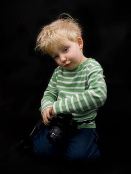 Smiling little boy with digital camera on black background. Boy have blue eyes and blond hair