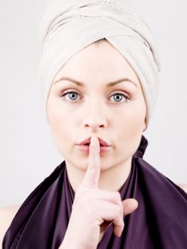 Portrait of beautiful young woman, showing gesture of silence