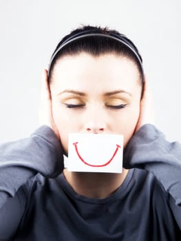 Portrait of beautiful young woman with fake smile. She's cover ears.