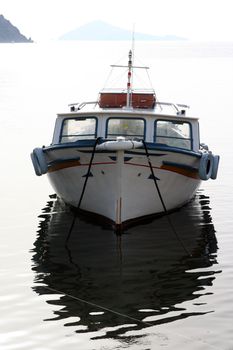 small wooden fishing boat anchored in sunset