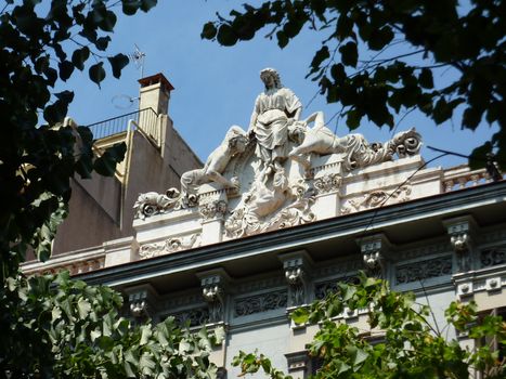 Sculpture of a woman and two men sirens on the top of a roof