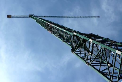 Big green crane with a background of a cloudy blue sky