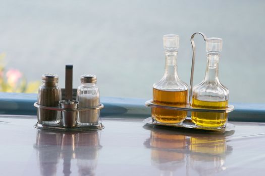 salt and pepper with salad and food sauce bottles winegar and oil detail from restaurant