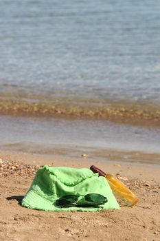 summer accessories green hat spectacles and sun oil by the sea