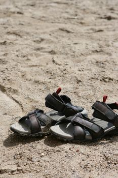 pair of sandals on the sandy beach with copyspace vertical