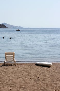 people swimming and  sunbed and surf board by the sea patmos island greece