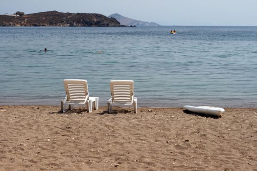 people swimming an dtwo sunbeds by the sea patmos island greece