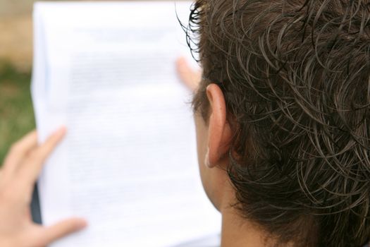 young man reading a document outdoors