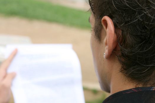 young man reading a document outdoors 