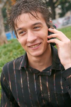 young man talking with cell phone outdoors happy