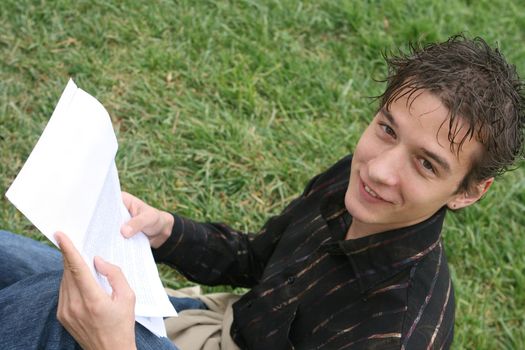 young student reading a document outdoors some good news and smile